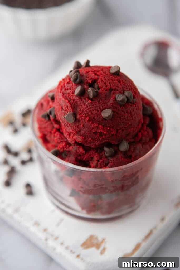 Edible red velvet cookie dough served in a small glass cup, ready to be eaten.