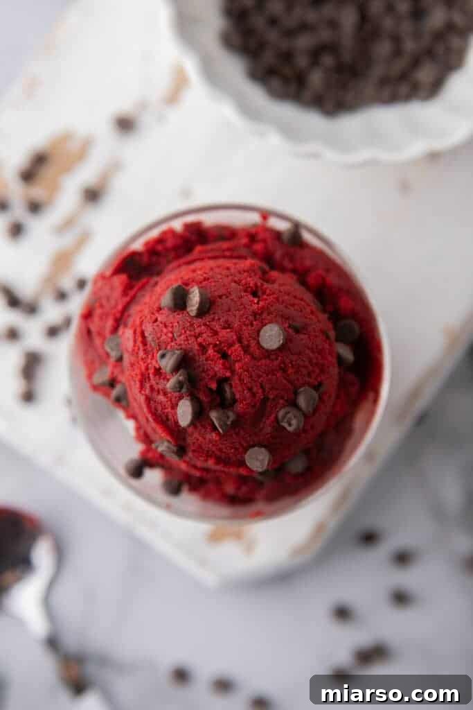 Overhead shot of safe to eat red velvet cookie dough in a bowl, with a spoon.