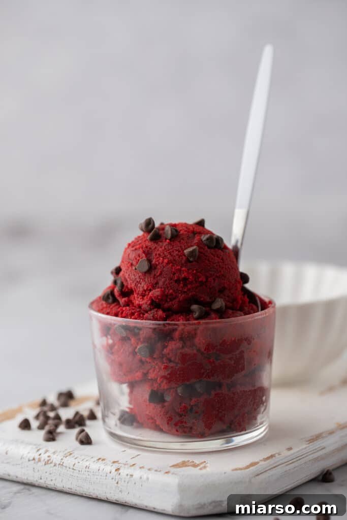 Straight on shot of cookie dough in a glass cup, showing its texture and vibrant color.