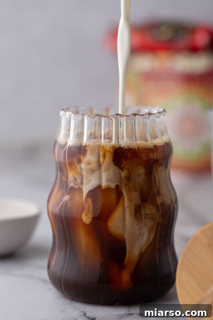 half and half being poured over coffee in a glass