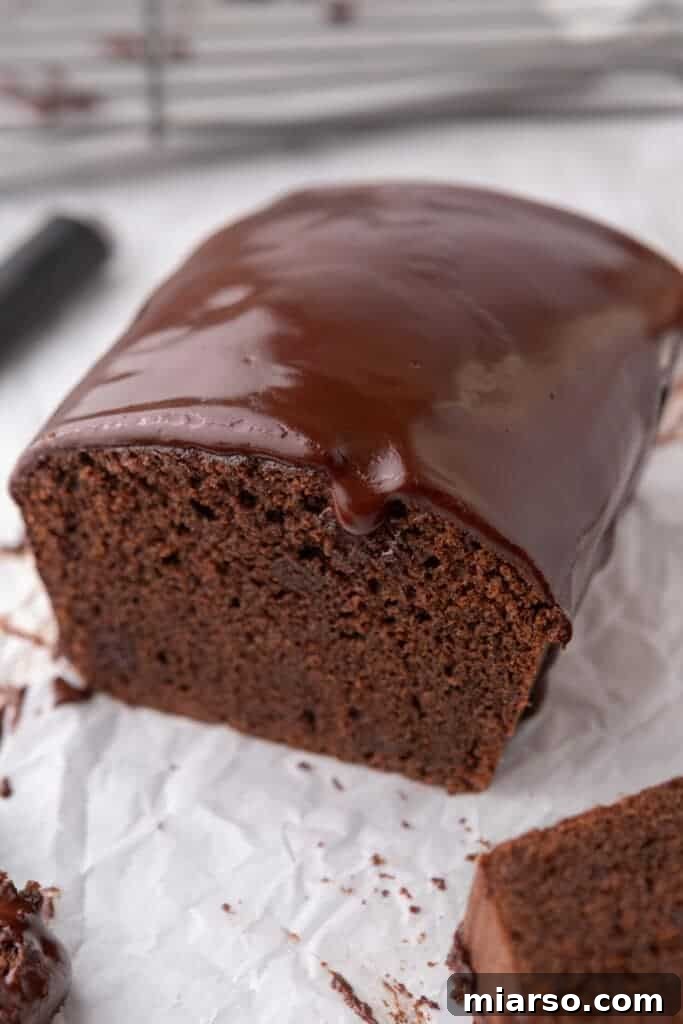 Ultimate Decadent Chocolate Pound Cake Recipe 2 A whole, glistening chocolate pound cake on parchment paper, ready to be sliced and enjoyed.