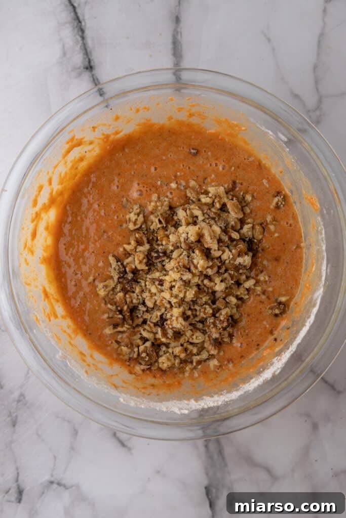 walnuts being mixed with the batter in a bowl