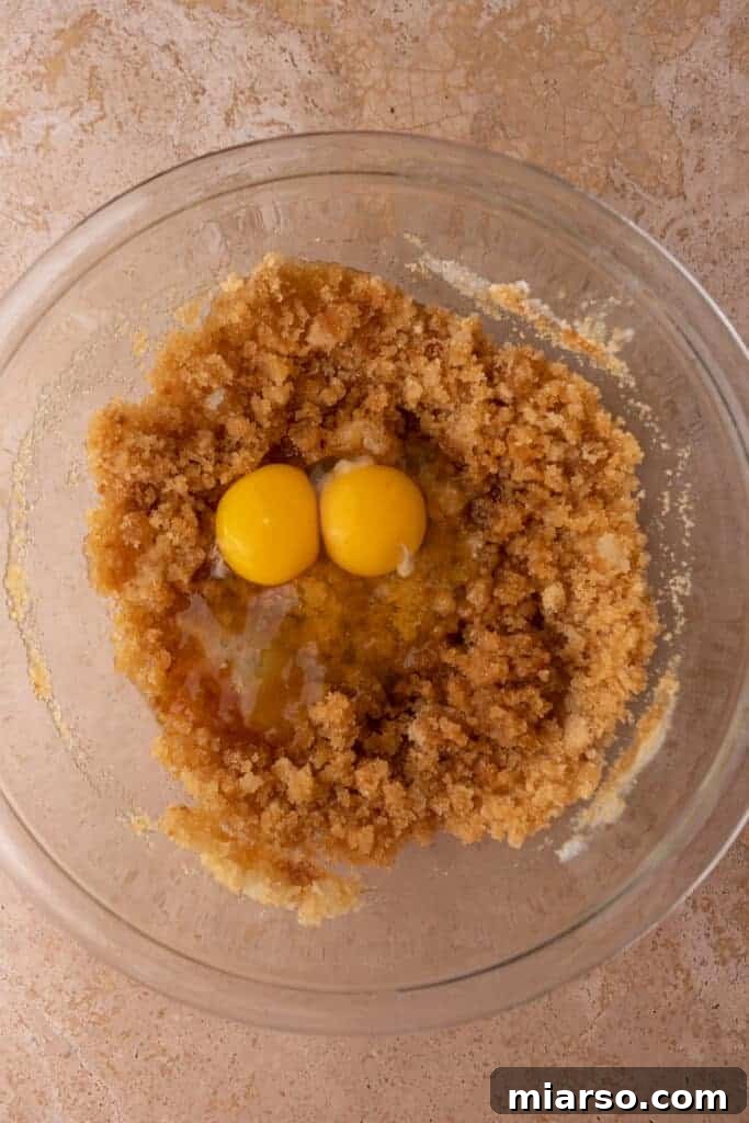 Gooey Giant Cadbury Mini Egg Skillet Cookie 6 Cracked eggs being added to the wet batter in a mixing bowl.