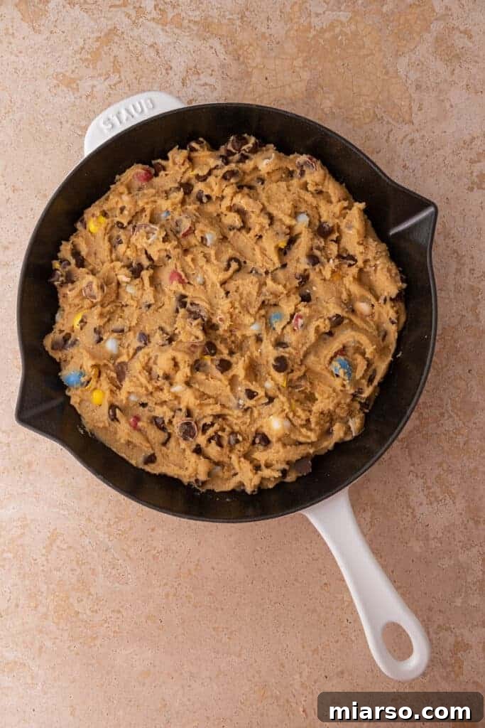 Gooey Giant Cadbury Mini Egg Skillet Cookie 9 Raw cookie dough pressed evenly into a cast iron skillet, ready to bake.