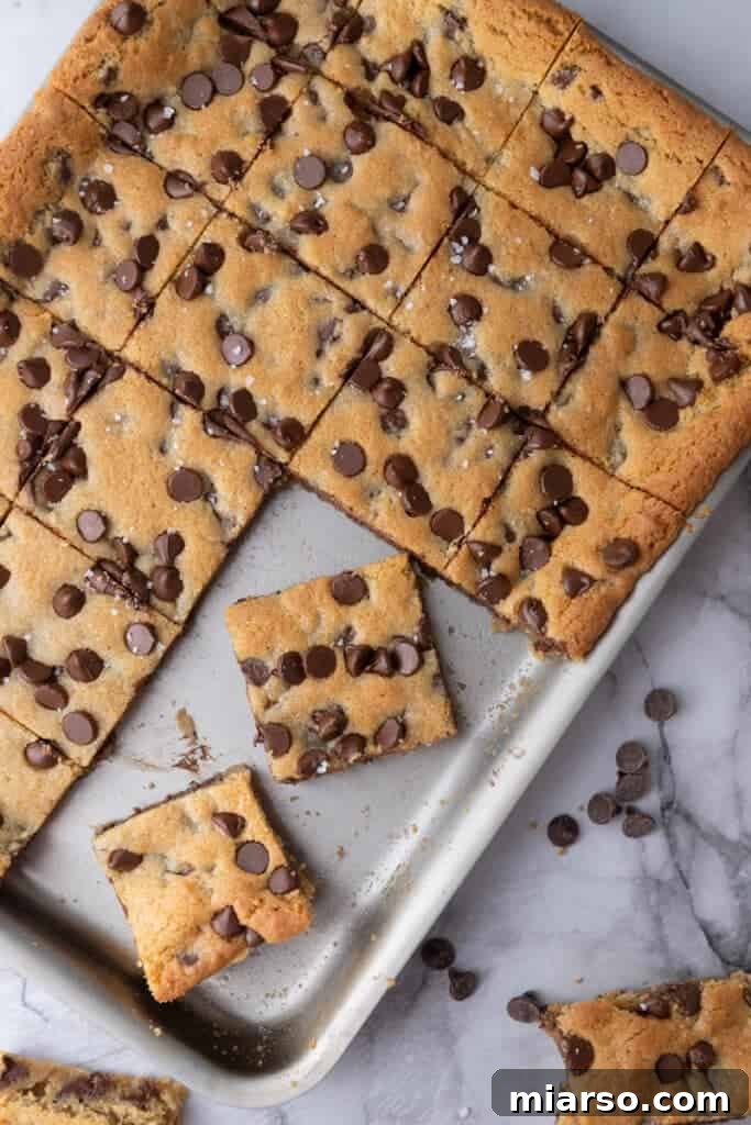 Nestle Toll House Cookie Bars Recipe - A pan of golden brown cookie bars with abundant melted chocolate chips on top, cooling on a wire rack, ready for slicing and serving.