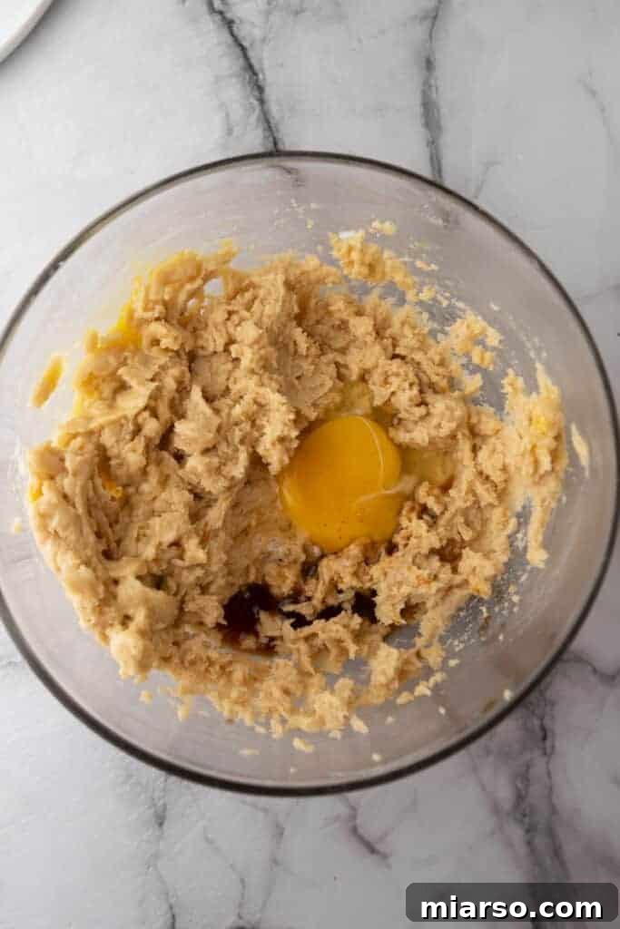 Close-up of softened butter and sugars being creamed together in a mixing bowl, showing a light and fluffy texture, indicating proper aeration.