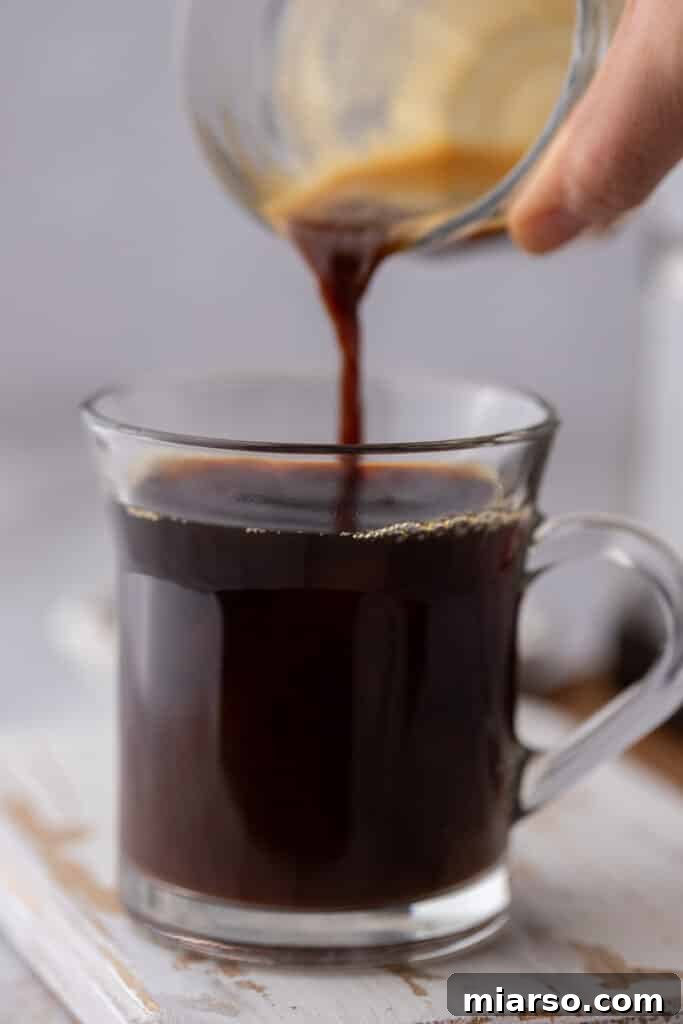 Espresso being poured from the cup into the glass to create Red Eye Coffee