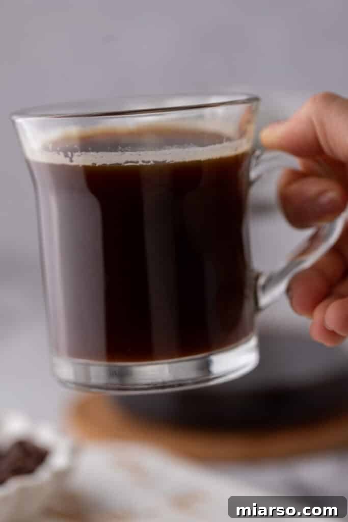 Red Eye Coffee Recipe in a glass being held up by a hand, ready to drink
