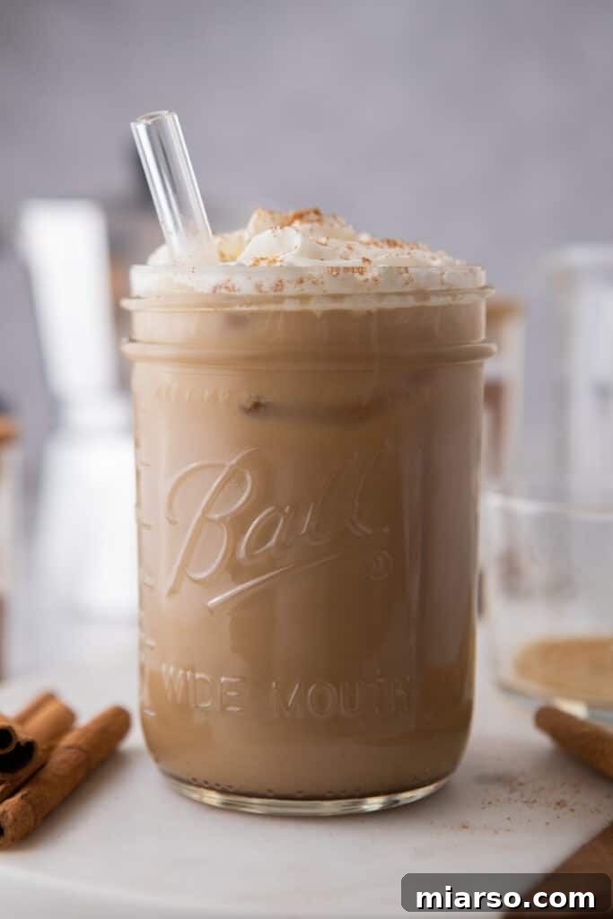 A perfectly crafted maple latte in a tall glass with a straw, showcasing its beautiful layers.