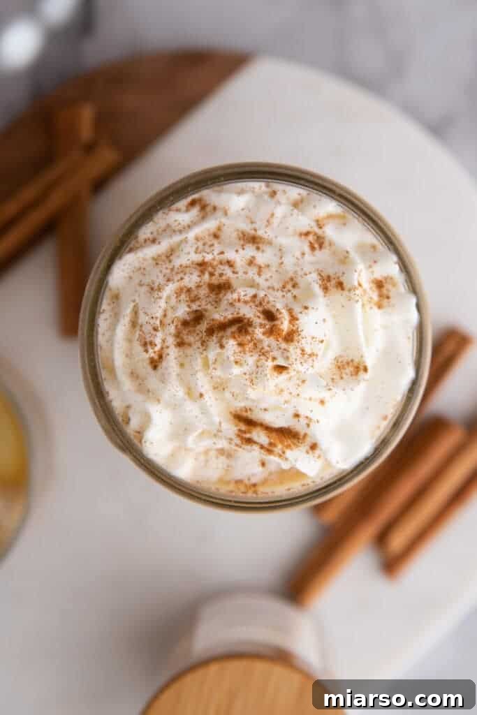 An overhead shot of a maple latte, with a swirl of whipped cream and a sprinkle of cinnamon on top.