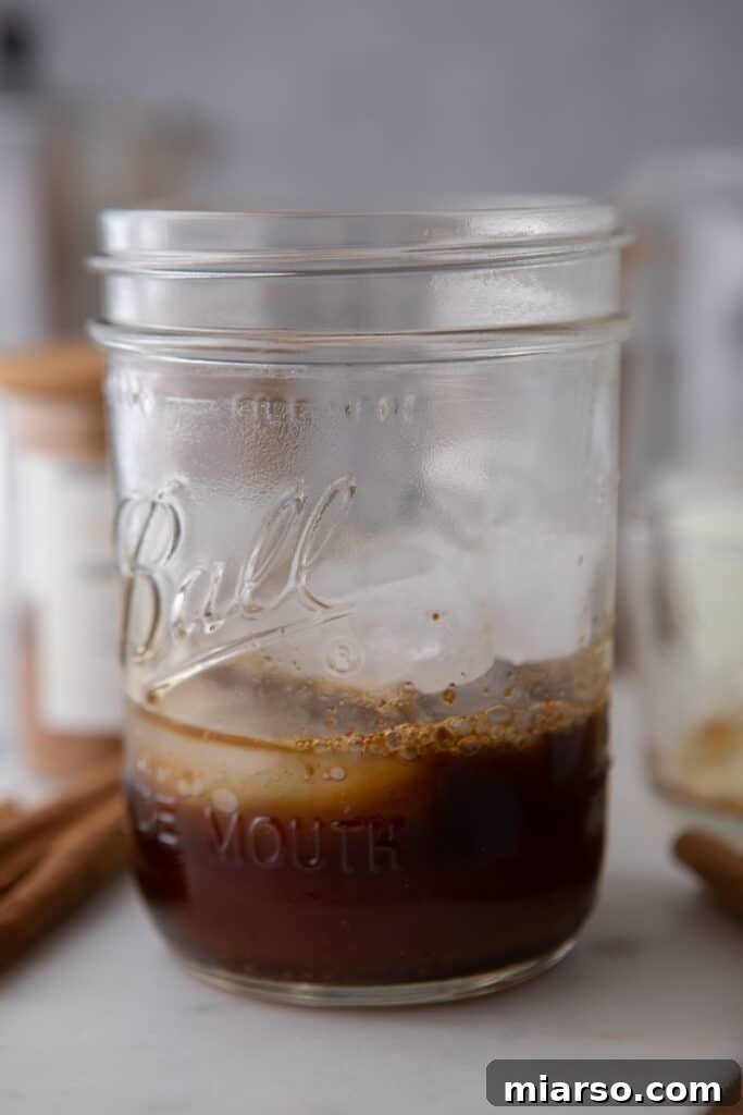 Espresso and ice cubes being carefully placed into a clear glass, ready for a refreshing iced latte.