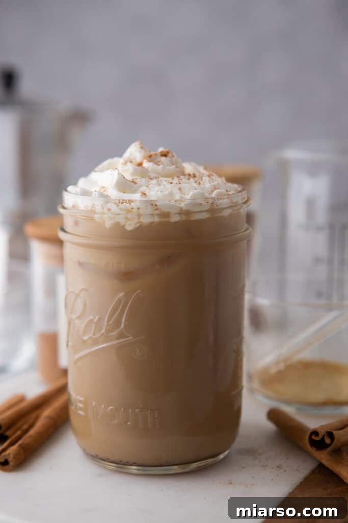 A side shot of a maple latte in a tall glass, highlighting its texture and inviting appearance.