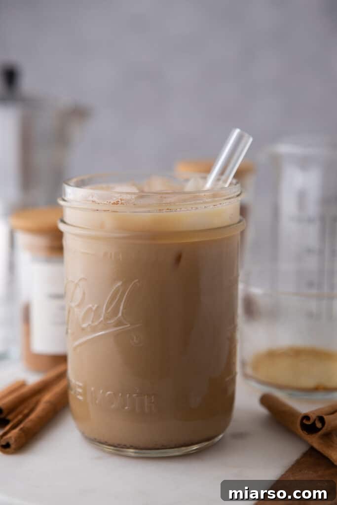 A close-up of a maple latte in a clear glass, with a straw and a rich, appealing color.