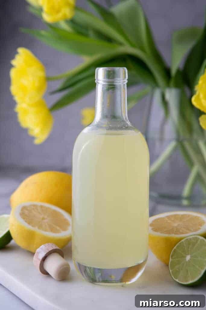 Bottle of homemade lemon sour mix on a wooden table, ready for cocktails