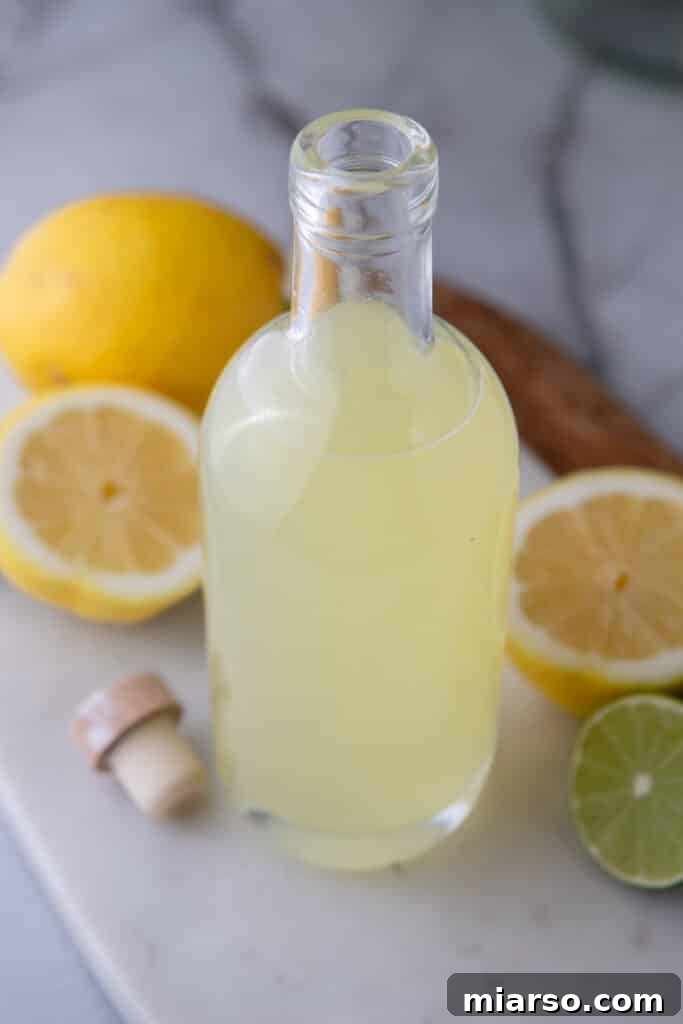 Overhead shot of the homemade lemon sour mix in a bottle with fresh lemons