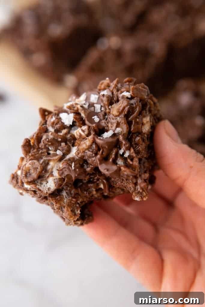 Ultimate Chocolate Rice Krispies Treats 4 a hand holding up a square of the brown butter chocolate rice krispies treats