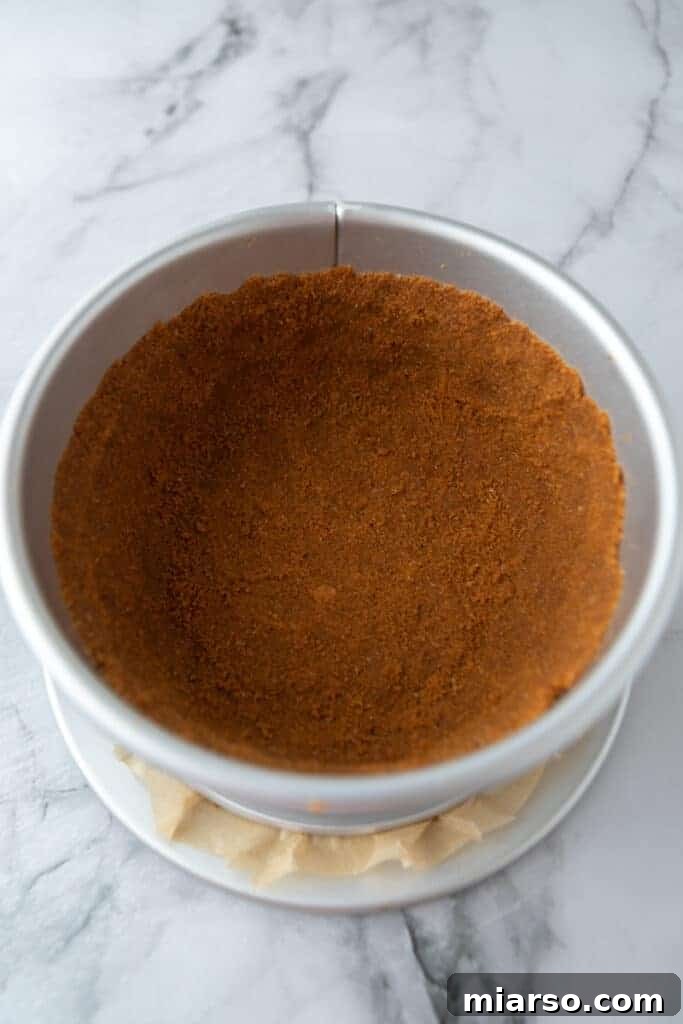 The Biscoff cookie crust pressed firmly into a springform pan, pre-baked to golden perfection.
