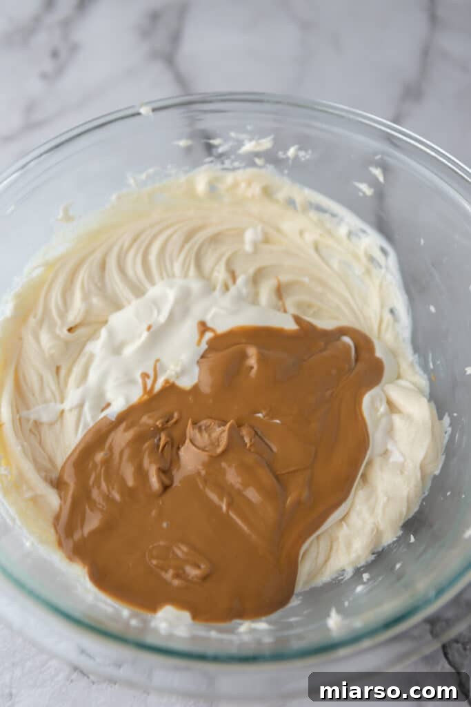 Cream cheese, sugar, and vanilla extract in a mixing bowl before being blended for the cheesecake filling.