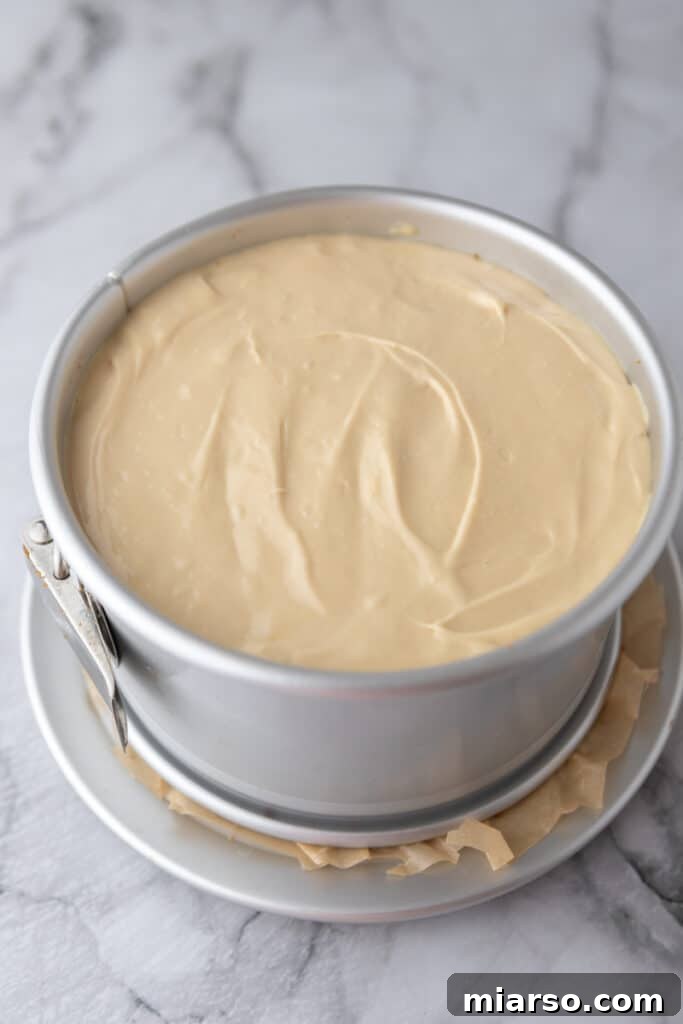 Smooth Biscoff cheesecake batter poured over the baked crust in a springform pan, ready for the oven.