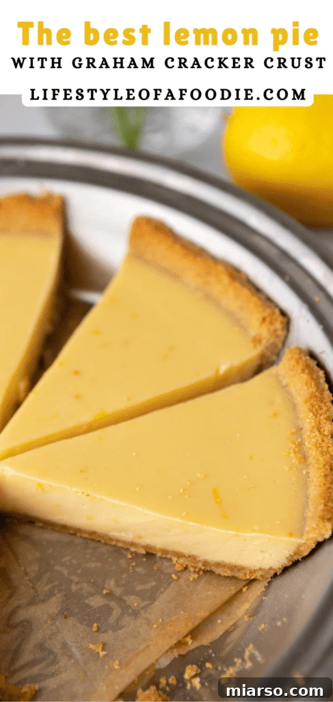 Pinterest pin showing an overhead view of a lemon pie with graham cracker crust, decorated with lemon slices and mint leaves