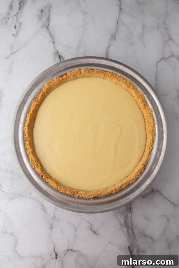 The unbaked lemon pie filling poured into the graham cracker crust in the pie pan, ready for the oven