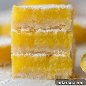 Three squares from the easy lemon bars recipe stacked on top of each other, dusted with powdered sugar.