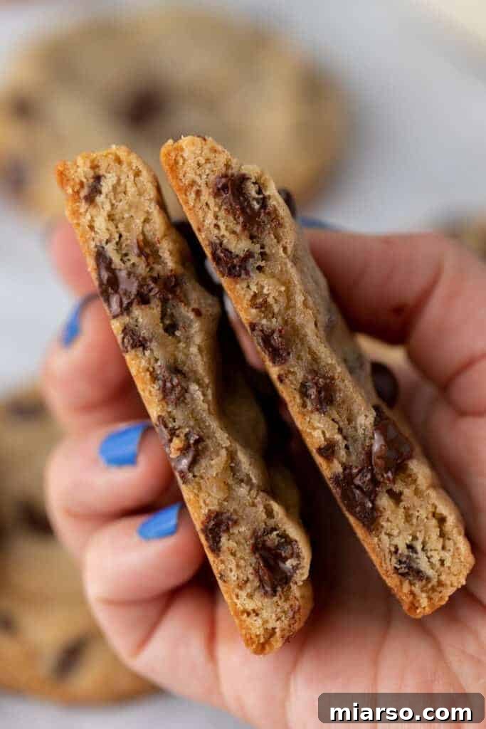 two halves of sourdough chocolate chip cookies being held up by a hand