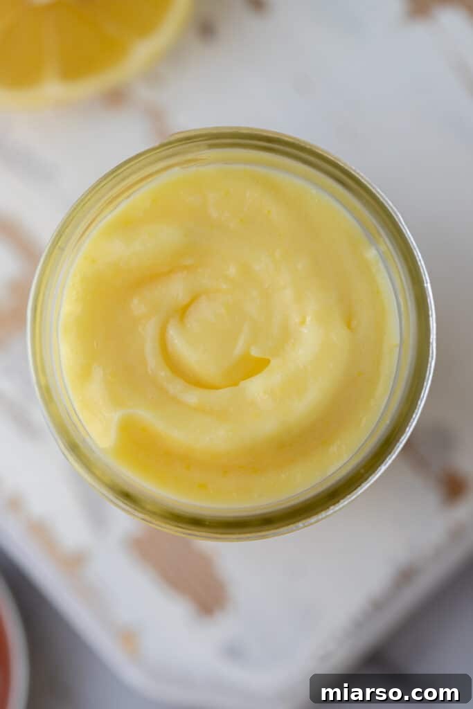 Microwave Magic: Luscious Lemon Curd in Minutes 11 Overhead shot of the microwave lemon curd recipe in a glass jar, garnished with a fresh lemon slice.
