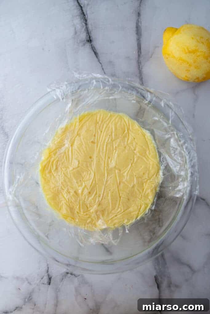 Microwave Magic: Luscious Lemon Curd in Minutes 9 Freshly made lemon curd in a bowl, with plastic wrap pressed directly on the surface, ready to chill.