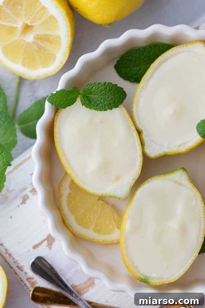 Overhead shot of an easy lemon posset recipe served in lemon halves, garnished with mint.