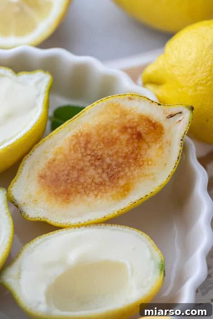An overhead shot of an easy lemon posset recipe served in lemon halves, with one featuring a golden, brûléed sugar crust.