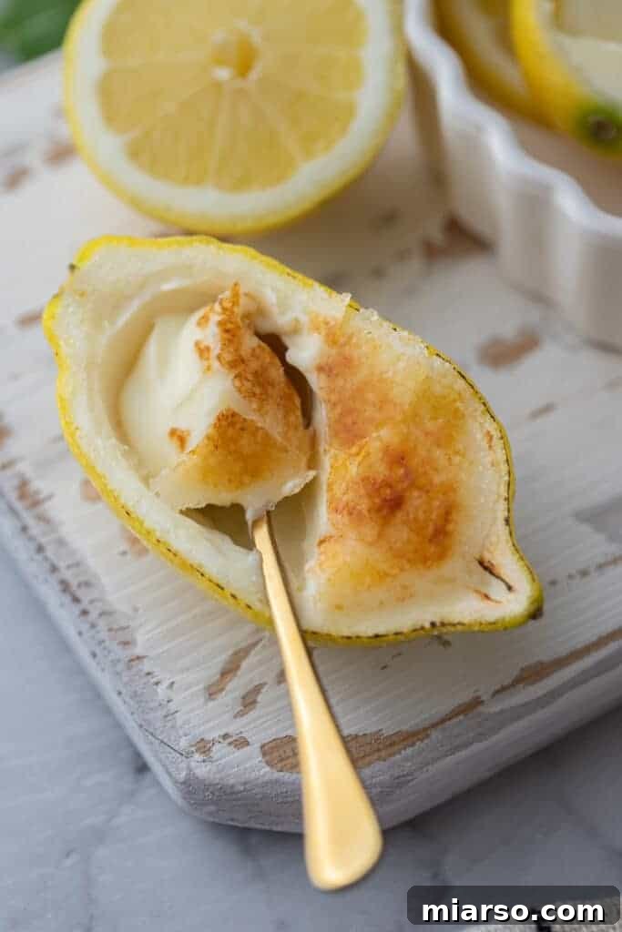 Overhead shot of a spoon scooping out a portion of creamy lemon posset from a lemon shell.
