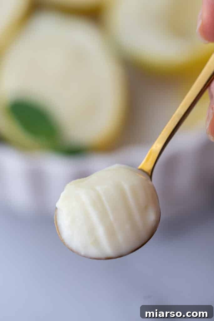 A spoonful of creamy lemon posset, showcasing its smooth texture and vibrant yellow color.
