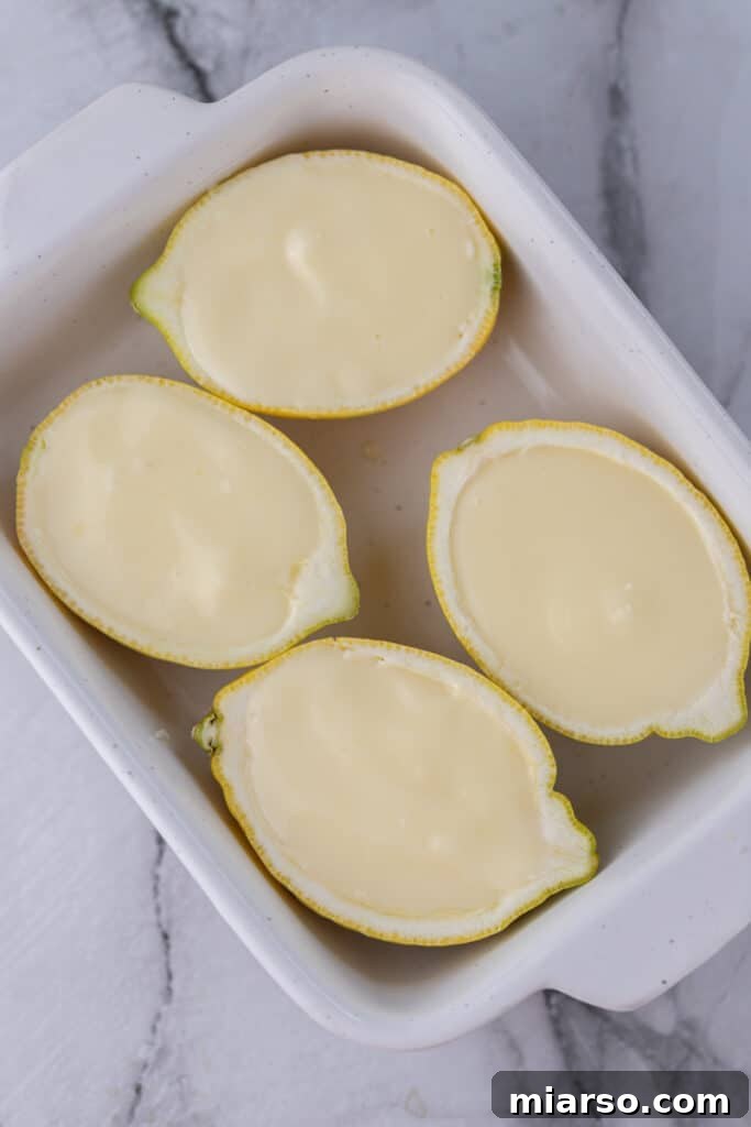 Citrus shells filled with creamy lemon posset mixture, ready for chilling.