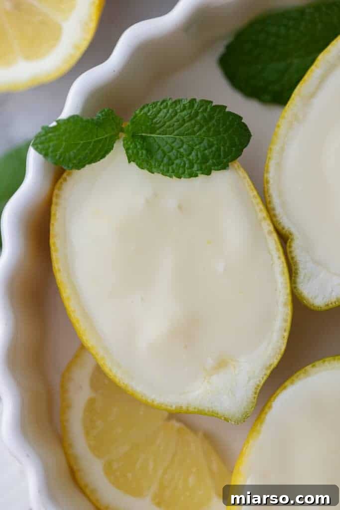Overhead shot of an easy lemon posset recipe served in lemon halves, garnished with fresh mint leaves.
