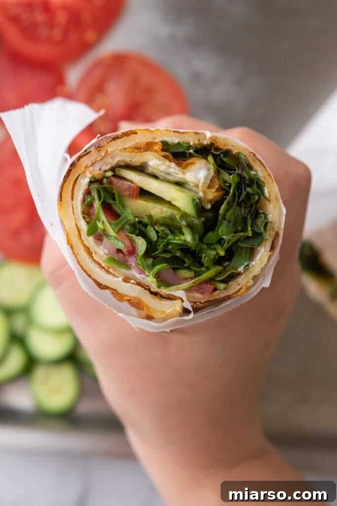 A hand holding a perfectly folded Viral Tiktok Cottage Cheese Wrap, showcasing its flexibility and delicious filling.