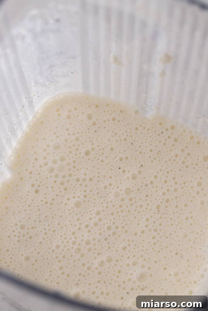 Another perspective of the smoothly blended wet ingredients in a blender, highlighting the uniform consistency.