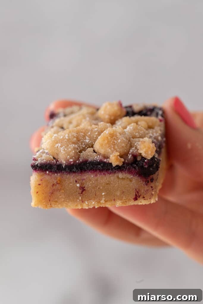 Hand holding a slice of blueberry blondie