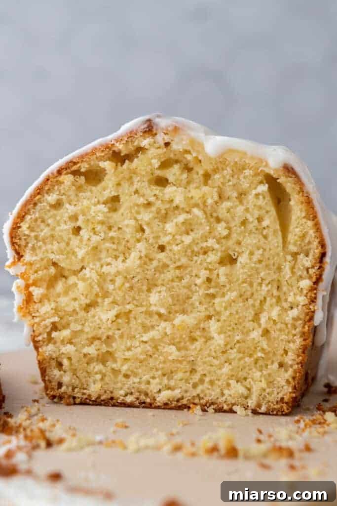 Close-up side view of a slice of Whole Lemon Blender Cake with glaze