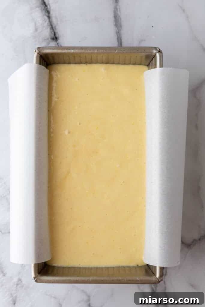 Smooth cake batter poured into a parchment-lined loaf pan