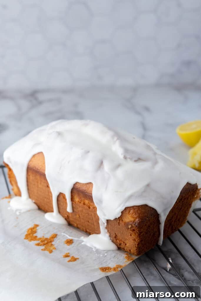 Lemon glaze being drizzled over a cooled lemon loaf cake