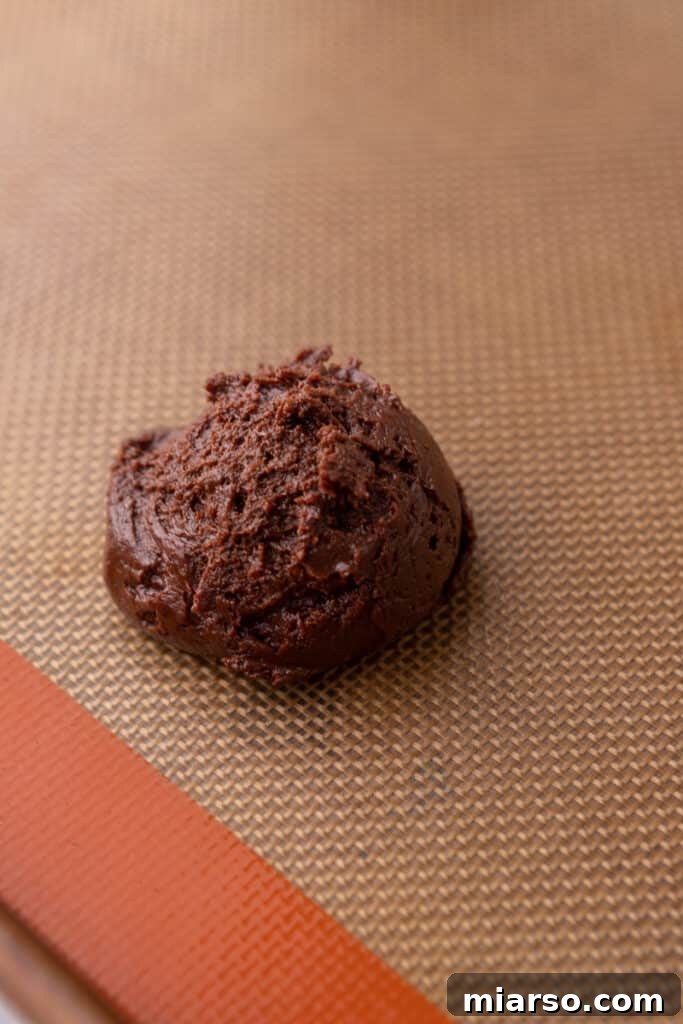 Chocolate cookie dough balls scooped onto a baking pan.