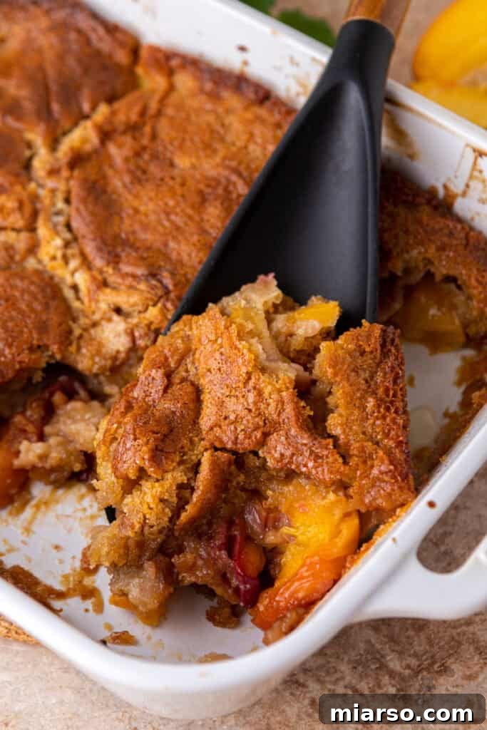 overhead shot of the old fashioned peach cobbler recipe being scooped by a spatula
