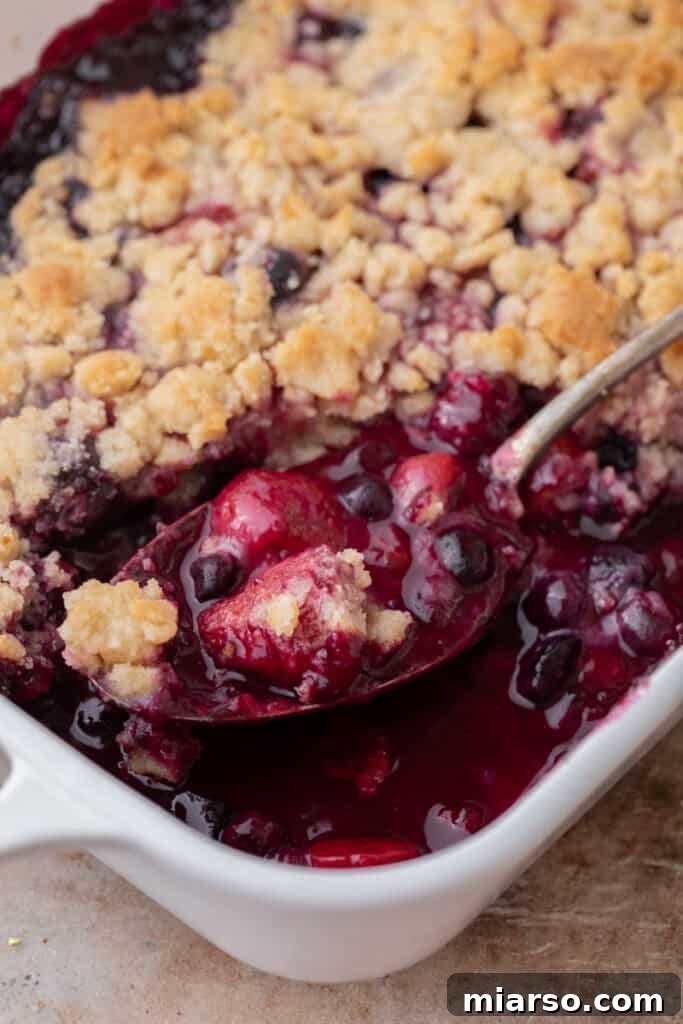 mixed berry cobbler recipe in a dish with a spoon