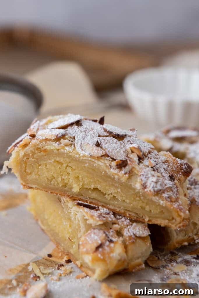 Two pieces of braided almond croissant danish stacked, showing filling