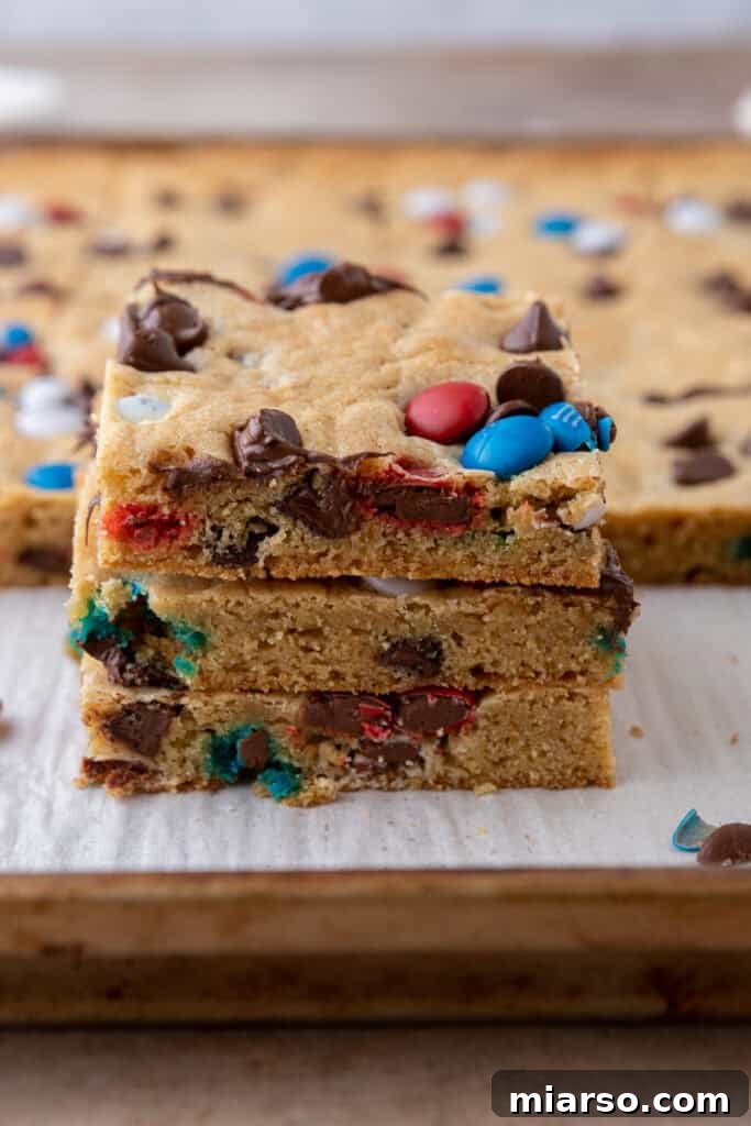 Straight-on shot of a large slab of patriotic red white and blue M&M's sheet pan cookies, cut into perfect squares.