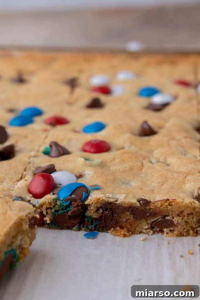 Detailed texture shot of the red white and blue M&M's sheet pan cookies, highlighting their chewiness and mix-ins.