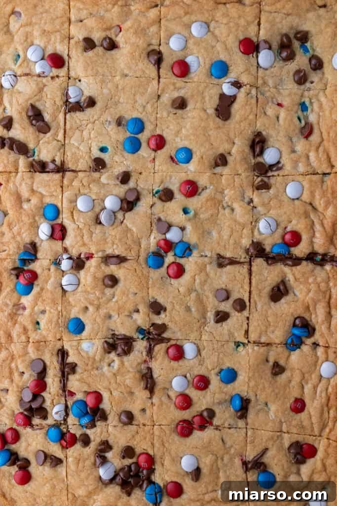 Close-up of patriotic sheet pan red white and blue M&M's cookie bars sliced into squares, ready to serve.