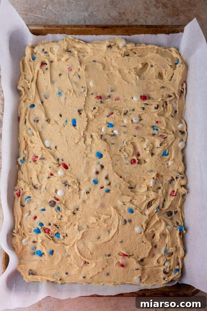Cookie dough spread evenly on a baking sheet, ready for the oven.