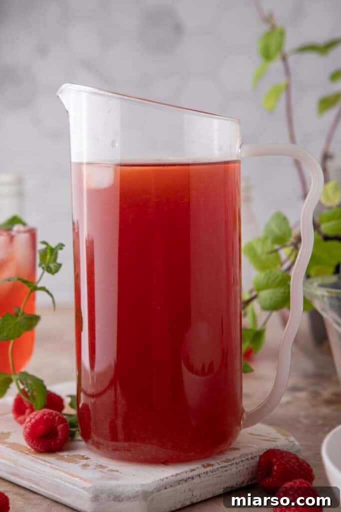 Raspberry Iced Tea Recipe in a pitcher, perfectly chilled with ice and fresh berries